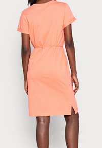 Lyhythihainen, korallinvärinen mekko, joka on valmistettu pehmeästä kankaasta. Mekossa on vyötärölle cinchattu malli ja sivuaukot liikkumisen helpottamiseksi. Yksinkertainen, rento muotoilu.