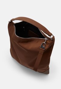 Hnědá nylonová taška přes rameno se zipem, koženými akcenty a odnímatelným popruhem; vnitřek obsahuje boční kapsu.