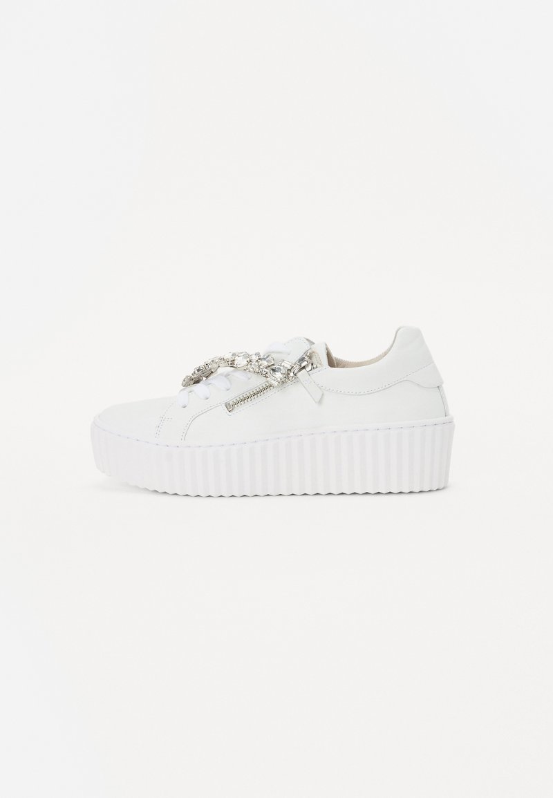 Hvide platform sneakers med en tekstureret sål, der har en dekorativ kæde og lynlåsdetalje på siden. Glat lædermateriale.