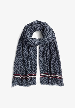 Κασκόλ σε ναυτικό μπλε χρώμα κατασκευασμένο από απαλό ύφασμα, με γεωμετρικό μοτίβο σε ανοιχτό μπλε και κόκκινη και λευκή ριγέ λεπτομέρεια στο τελείωμα.