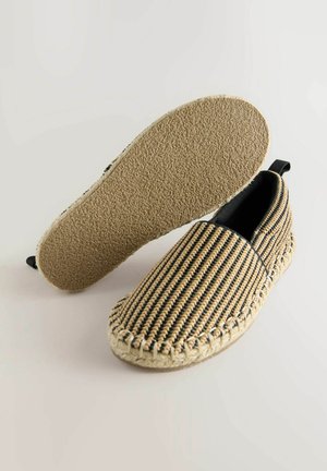 Geweven instapschoenen met een gestreept zwart en beige patroon, een gestructureerde juten zool en een zwarte elastische band bij de hak voor gemakkelijk aan- en uittrekken.