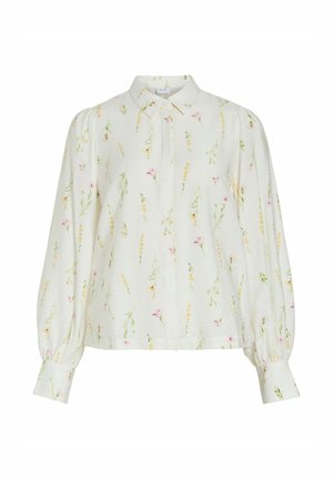 Blouse blanche à manches longues avec col pointu, délicat motif floral rose, jaune et vert, et poignets boutonnés.