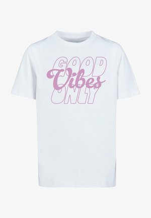 Balta medvilnė t-shirt su trumpomis rankovėmis. Savybė - rožinė užrašas "TIK GEROS VIBRACIJOS," su stilizuotu šriftu ir skirtingo dydžio raidėmis.