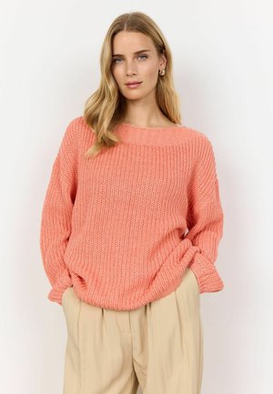 Koralfarbener gestrickter Pullover mit weitem Bootsausschnitt und lockerer Passform. Mit geripptem Muster und Bündchen ausgestattet. Kombiniert mit beigen hochgeschnittenen Hosen.