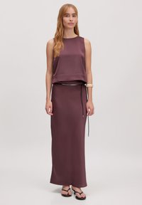 Satin twee-delig outfit in diep paars; mouwloos top met een vloeiende stijl en een bijpassende lange rok; heeft een trekkoord in de taille.
