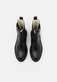 Botas de tobillo de cuero negro con una textura suave, paneles laterales elásticos y un suave forro de piel sintética, con una puntera redondeada y una suela texturizada.