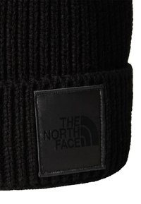 Musta neulottu pipo, jossa on ribbikuvio ja käännetty reunus. Varustettu suorakulmaisella mustalla nahkalaatalla, jossa on "THE NORTH FACE" -logo.