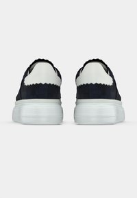 Συνθετικά σουέντ αθλητικά παπούτσια σε ναυτικό μπλε με λευκή κυματιστή λαιμόκοψη και χοντρή, διαφανή ελαστική σόλα. Διαθέτουν λείο υλικό και στρογγυλεμένο σχήμα.