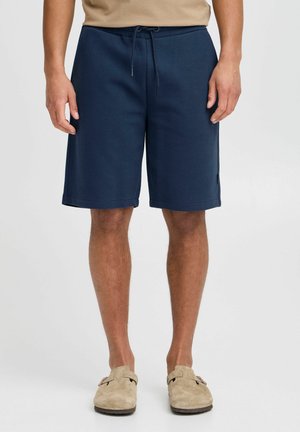 Marinblå shorts med ett texturerat mönster, elastisk midja med snörning, sidofickor, skräddarsydd passform och längd till mitt på låret.