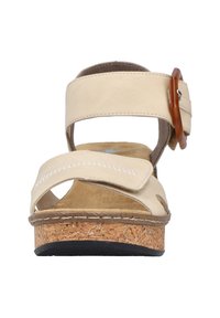 Sandales beiges avec un design à sangle croisée, semelle en liège et accent de boucle réglable. Présente un dessus doux semblable à du daim et des détails cousus.