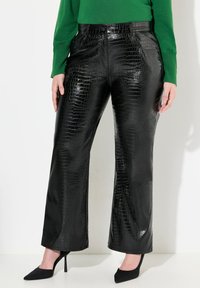Pantalons noirs taille haute avec une texture brillante en relief crocodile, à jambe large et associés à des escarpins noirs à bout pointu.