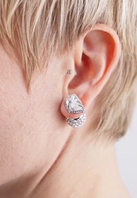 Pendientes de gota de cristal con forma de lágrima, montura de plata y un acento circular texturizado cubierto de pequeñas piedras transparentes.