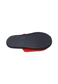 Scarpa rossa con suola in gomma nera testurizzata che presenta motivi circolari. La parte superiore è in un materiale liscio con cuciture a contrasto.