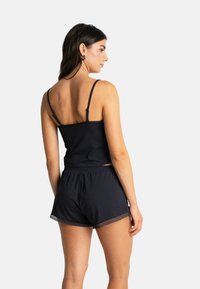 Camisole en coton noir avec bretelles ajustables et short assorti ornés de dentelle. Design simple et coupe décontractée.