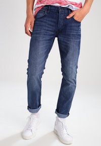 Blå denimjeans med rak passform, med en femficksdesign, något urtvättad tyg och uppvikt fåll. Vald med vita sneakers.