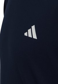 Tmavě modré sportovní látky s bílým třípruhovým logem na boku, hladká textury, přiléhavý střih, vhodné pro sportovní oblečení.