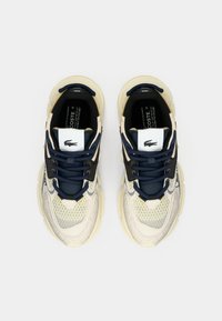 Sneakers Lacoste in crema e blu navy. Parte superiore in tessuto a rete e tessuto testurizzato, suola spessa crema, accenti neri e linguetta con marchio.