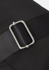 Black fabric with a textured finish, featuring a silver rectangular buckle on a wide strap, and smooth surface details.