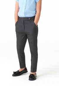 Persoană îmbrăcată în pantaloni eleganți gri închis, cu buzunare frontale, o bluză scurtă cu mânecă, de culoare albastru deschis, și mocasini negri cu ciucuri.