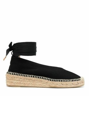 Chaussure espadrille noire avec semelle en jute tissée et lien à nouer à la cheville, talon compensé plat et bout fermé.