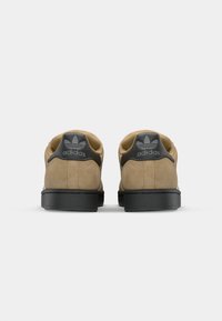 Brown suede shoes with a black rubber sole and matching heel tab, featuring a textured design and Adidas logo on the back.