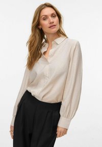 Hele beež värviga nööbitav pluus, millel on pikad õhulised varrukad, peened sädelevad detailid ja sile pind. Kaasas paar musti pükse.