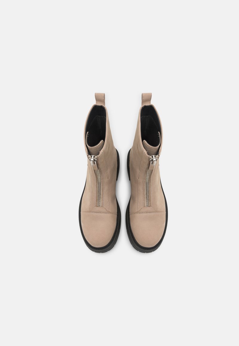 Beige Wildleder-Stiefeletten mit einem seitlichen Reißverschluss, runder Zehenpartie, kontrastierender schwarzer Sohle und einem Ziehlappen an der Ferse für ein einfaches An- und Ausziehen.