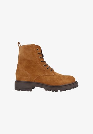 Bota de tobillo de ante marrón con cordones, suela oscura y rígida, y tirador en el talón, mostrada en perfil lateral sobre fondo blanco.