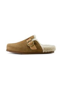 Brown suede slipper featuring a soft, fluffy white lining, a round metal buckle accent, and a slightly curved shape. Flat sole design.