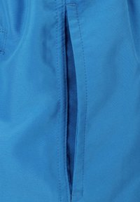 Blauwe stof met een gladde textuur en zichtbare stiksels; heeft een ongeopende opening voor toegang tot de zak.