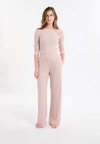 Set di abbigliamento lounge rosa chiaro a costine, con maniche lunghe, top leggermente corto con dettaglio di bottoni laterali e pantaloni a gamba larga con orli sfrangiati.