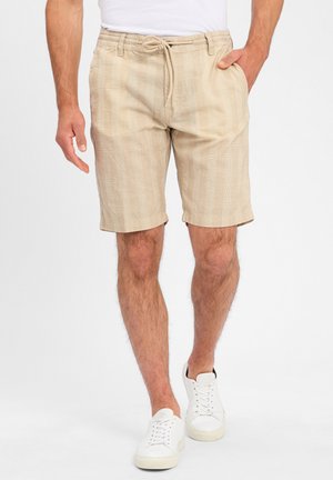 Beige linen shorts with an elastic waistband and drawstring. Casual fit, knee-length, featuring a subtle textured pattern.