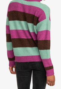 Pull en maille présentant de larges rayures turquoise, magenta et marron, avec un col haut et des poignets côtelés. Texture douce, coupe décontractée.