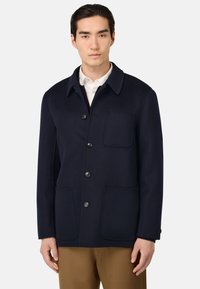 Marine spalvų vilnos mišinuko paltas su smailiu apykakle, priekiniais mygtukais, dviem didelėm kišenėm ir viena krūtine kišene. Lygus paviršius ir struktūrizuotas dizainas.