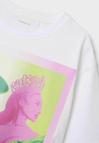 Biała koszulka z kolorową grafiką przedstawiającą różową kobietę noszącą ozdobną koronę, na tle ramki w kolorze zielonym i różowym.