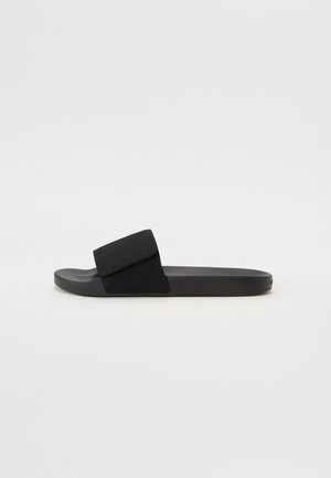 Sorte sandaler i svart med en myk tekstiloverdel og flate gummisul. Designet har en stropp med borrelås og en glatt overflate.