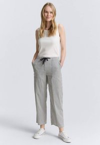 Bawełniane, lekkie spodnie w paski z talią na sznurek, bocznymi kieszeniami i krótkim zakończeniem. Noszone z dopasowanym białym topem na ramiączkach i sportowymi butami.