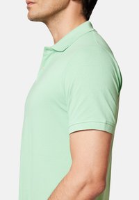Jasnozielona koszulka polo wykonana z teksturowanej tkaniny, z klasycznym kołnierzykiem i krótkimi rękawami. Zaprojektowana w luźnym kroju.