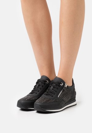 Baskets noires avec détails en mesh, bout rond, accent de fermeture éclair argentée et semelle en caoutchouc plate. Lacets et œillets métalliques complètent le design.