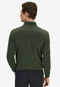 Mörkgrön stickad tröja med hög krage och långa ärmar, med en slät textur och ribbade muddar och nederkant.