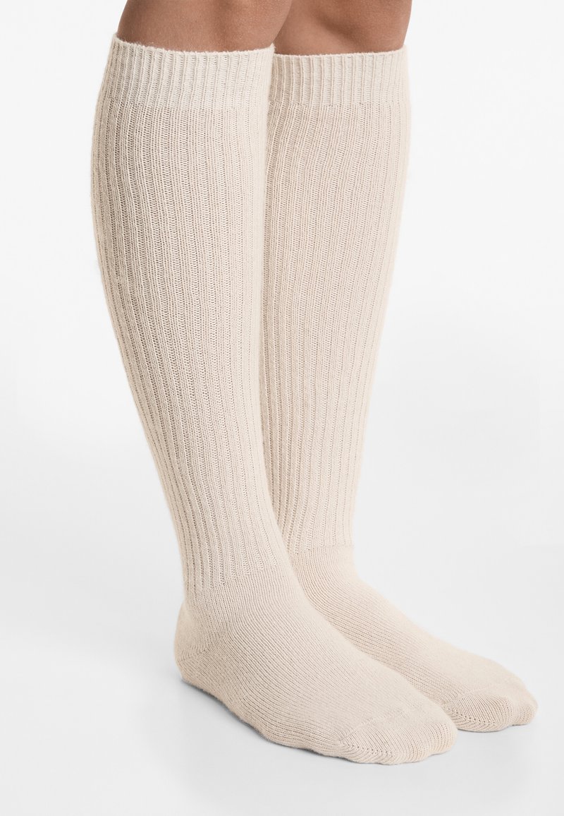 Knæhøje beige sokker med ribbet tekstur, lavet af blødt strikmateriale, med forstærket tå og hæl for holdbarhed.