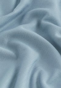 Měkká, světle modrá látka s hladkým povrchem, s jemným žebrováním a mírným skládáním, které zdůrazňuje její lehkost a pružnost.