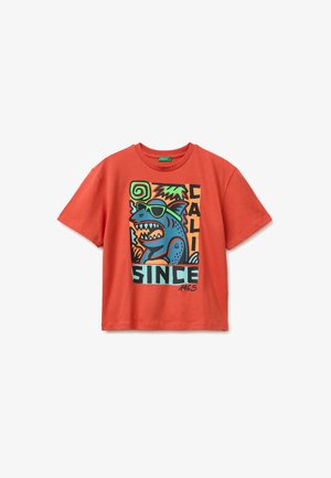 T-shirt orange à manches courtes avec un graphisme de requin bleu portant des lunettes de soleil vertes, entouré de feuilles de palmier, avec le texte "CALI SINCE 1965."