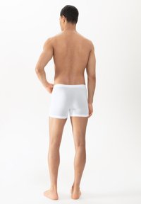 Caleçons boxers en coton blanc avec une texture lisse et une taille élastique, vus de dos, mettant en valeur un design ajusté.