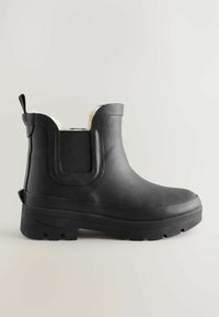 Bottes de cheville en caoutchouc noir avec une finition texturée, un tirette et une douce doublure blanche. Semelles épaisses avec un profond profil pour une bonne adhérence.