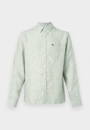 Zaļi un baltu svītru garām piedurknēm krekls ar pogām, krūšu kabatu un nelielu zaļu logotipu kreisajā pusē. Izgatavots no kokvilnas materiāla.