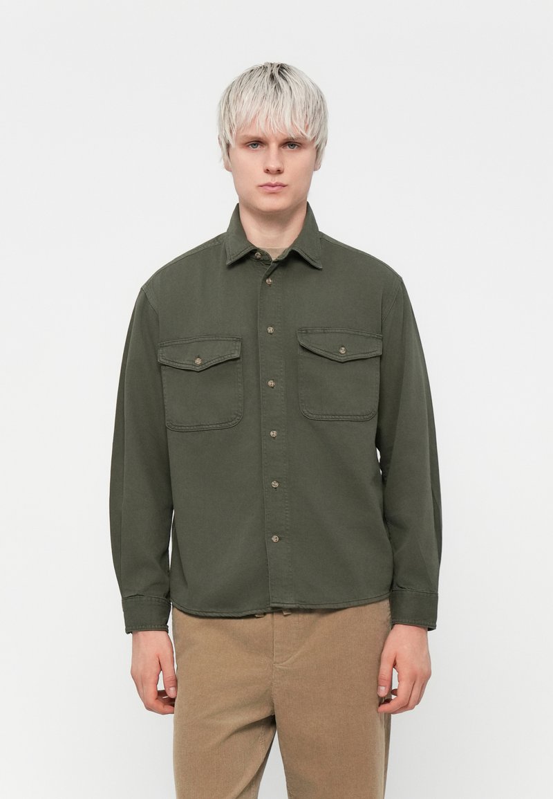 Olive green button-up shirt with two front pockets, long sleeves, a collar, and a relaxed fit. Mildly textured fabric.