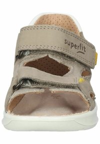 Sandal en marron clair avec sangle réglable à boucle, design ouvert, intérieur perforé et semelle blanche ; présente un logo sur le haut.