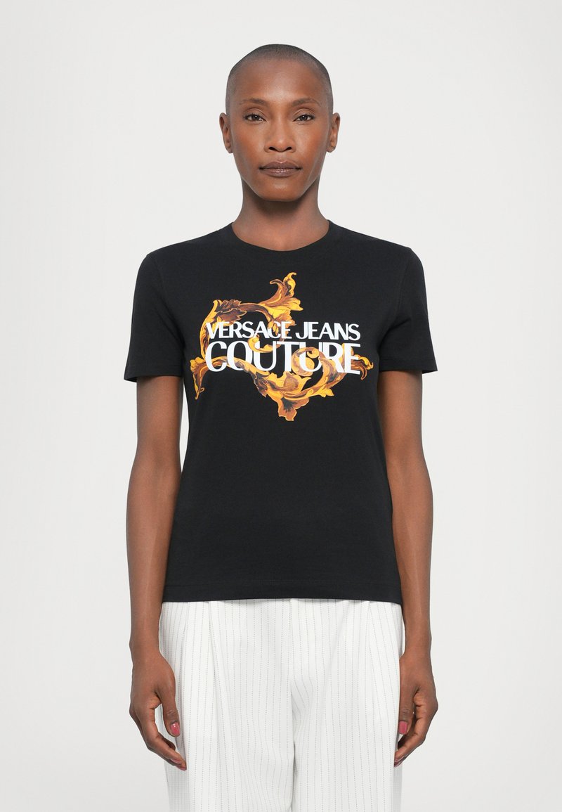 Svart bomull t-skjorte med et fargerikt barokk-inspirert design og teksten "VERSACE JEANS COUTURE" i hvitt. Korte ermer, rund hals.