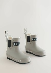 Grijze rubberen enkelboots met een witte pluizige voering, zwarte elastische panelen en een zwarte logo band. Heeft een gestructureerde zool voor grip.